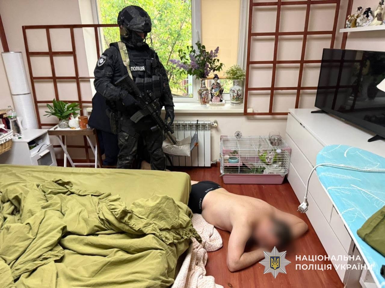 Одни із фігурантів провадження лежить на землі, позаду нього - боєць спецпідрозділу поліції