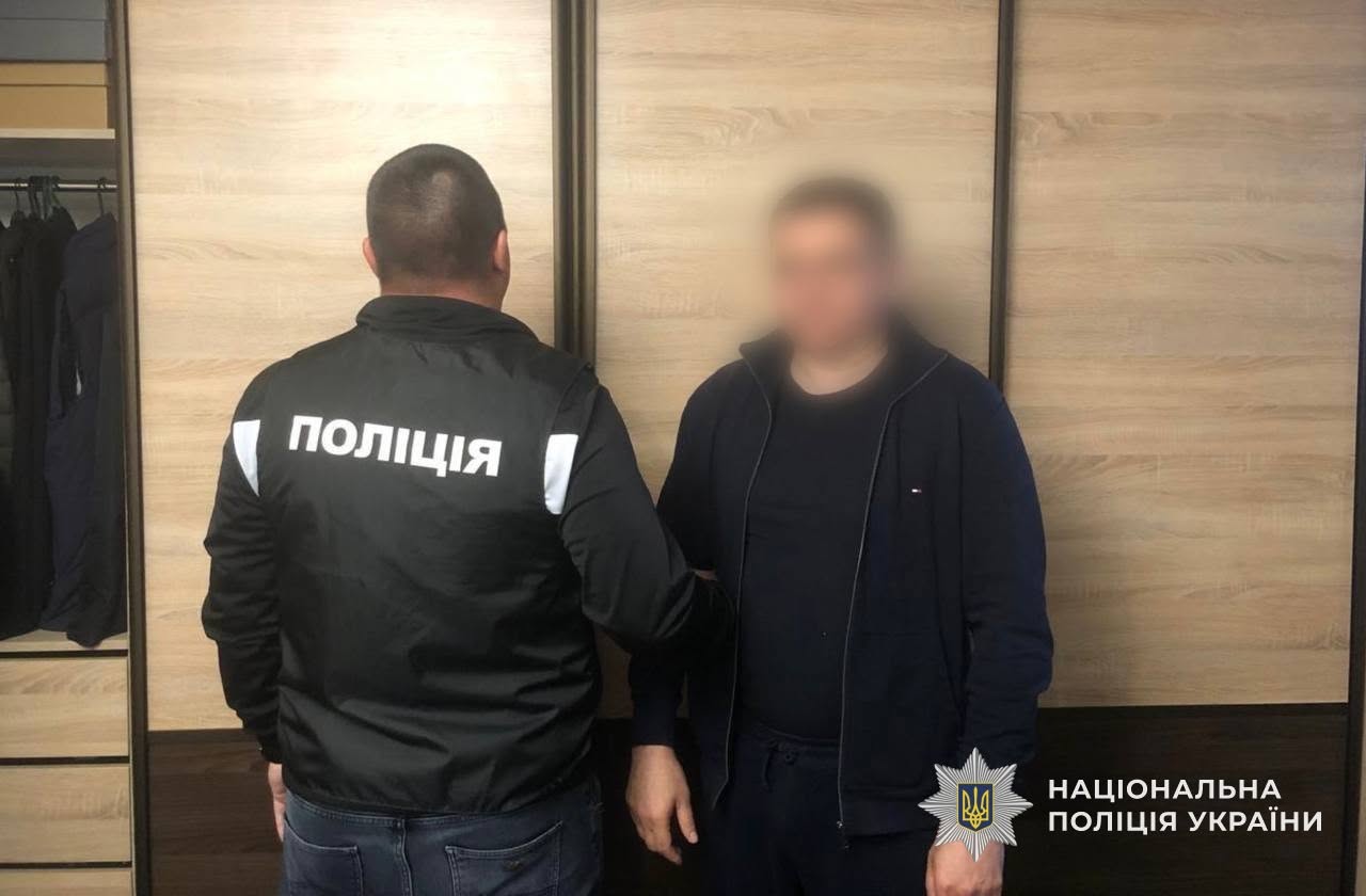 Співробітник поліції тримає одного із затриманих фігурантів