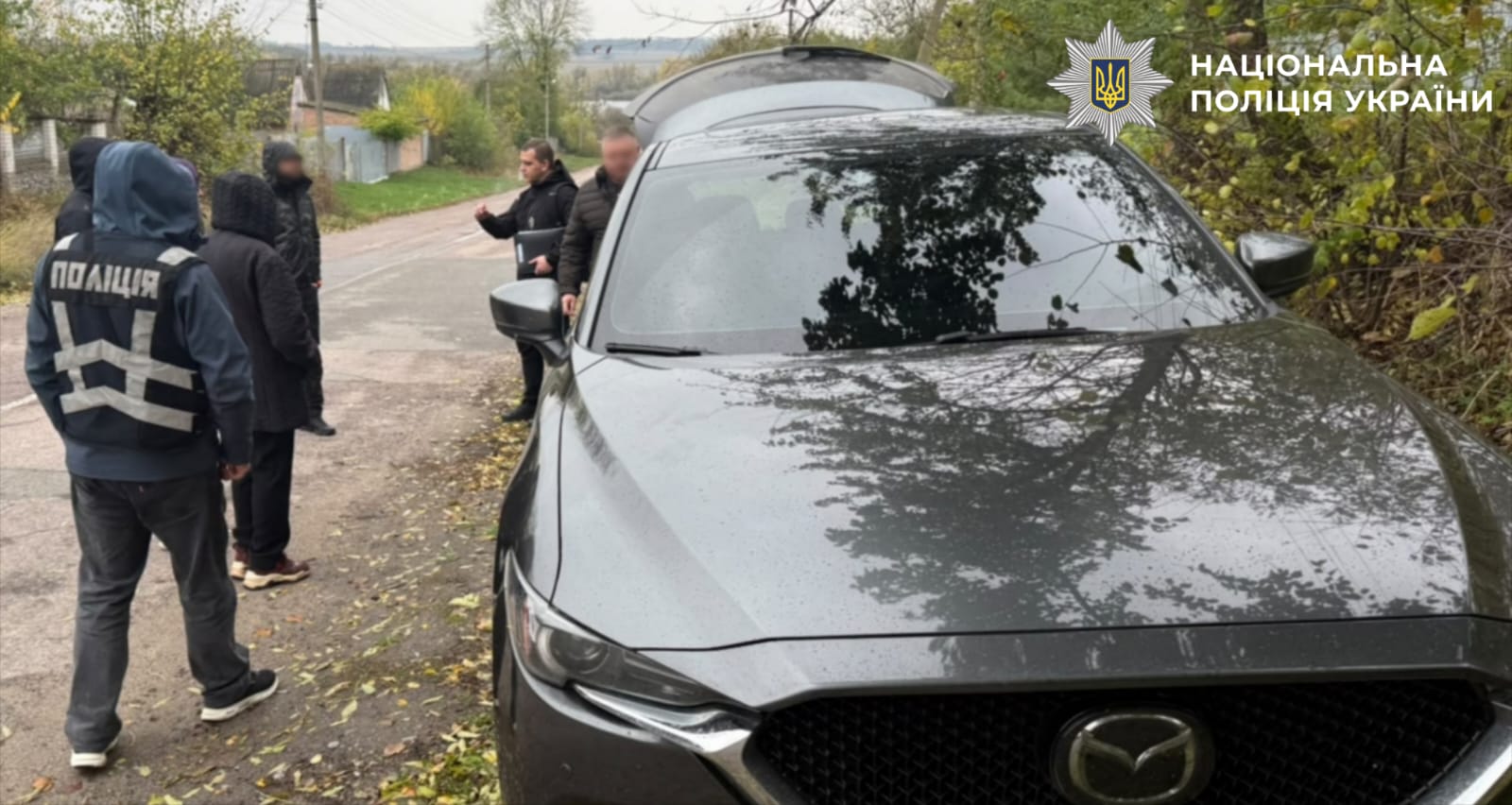 На фото один з фігурантів, правоохоронці та транспортний засіб.