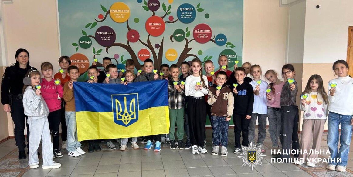 Фото поліцейської і дітей класу з державною символікою 