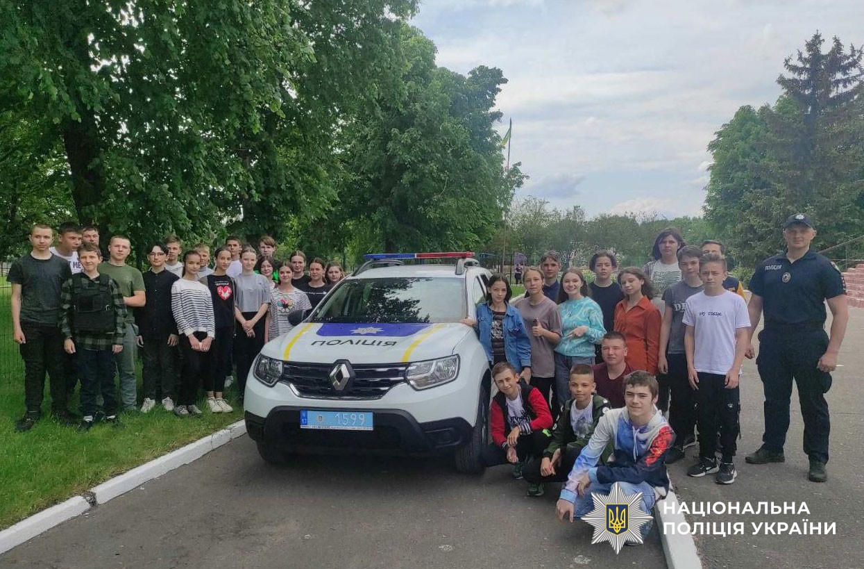 діти разом з поліцейським біля службового авто