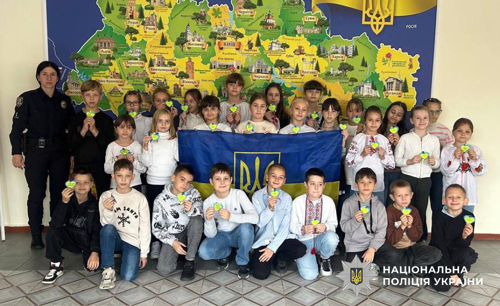 Фото поліцейської і дітей класу з державною символікою 