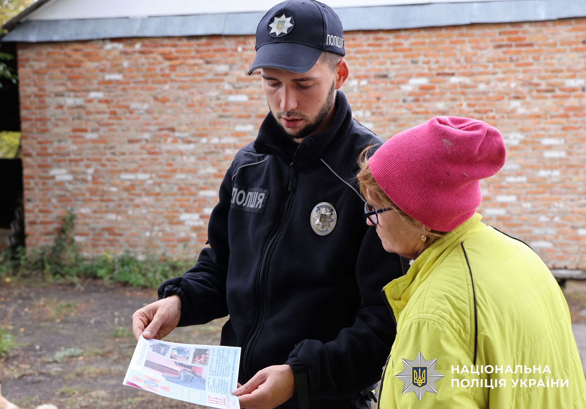Поліцейський офіцер громади розяснює місцевій мешканці про наслідки спалення сухої трави