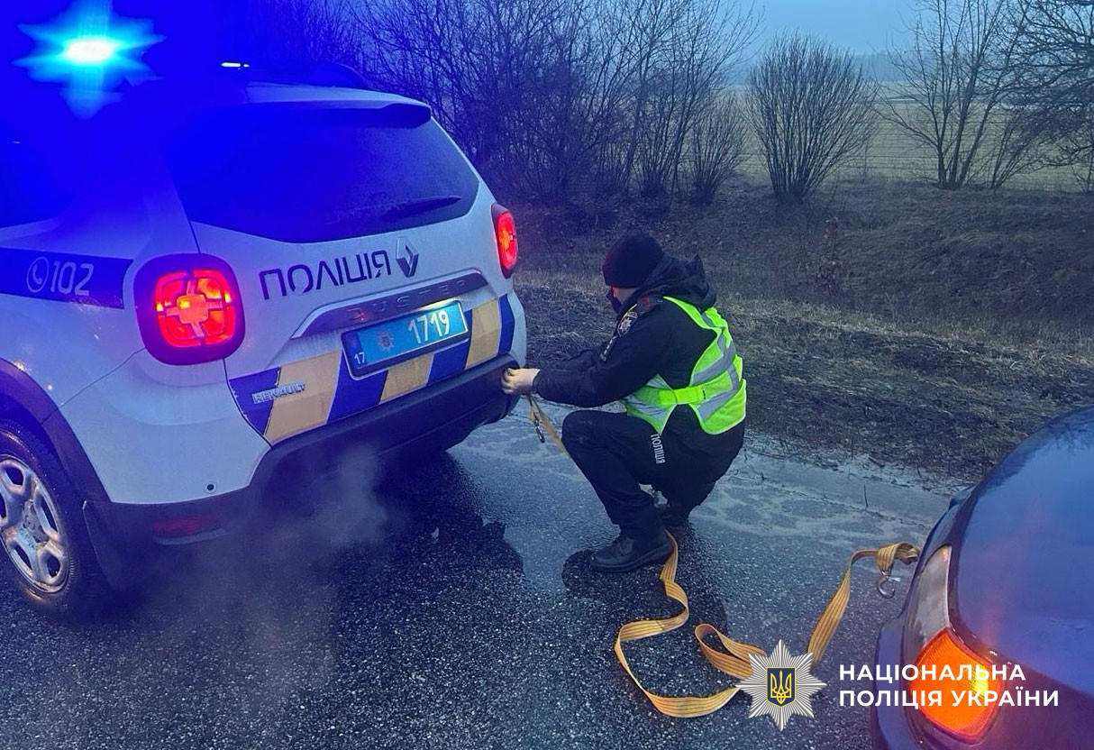 поліцейський допомагає буксирувати авто