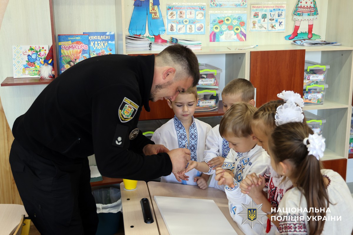 Поліцейський фарбує руки дітей у блакитний колір