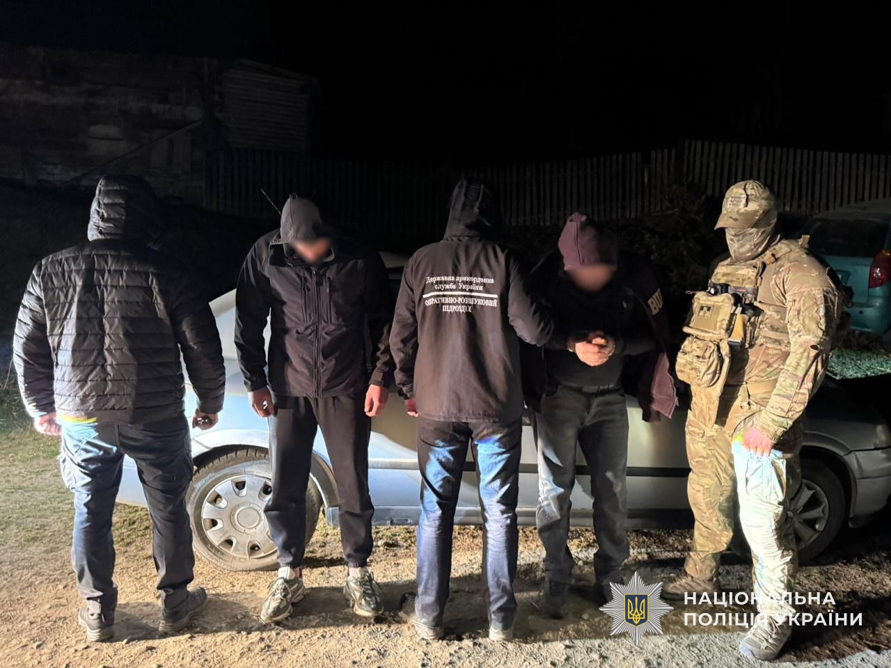 Правоохоронці тримають за руки мешканця села Чорна Тиса, підозрюваного в незаконному переправленні особи через кордон та його клієнта