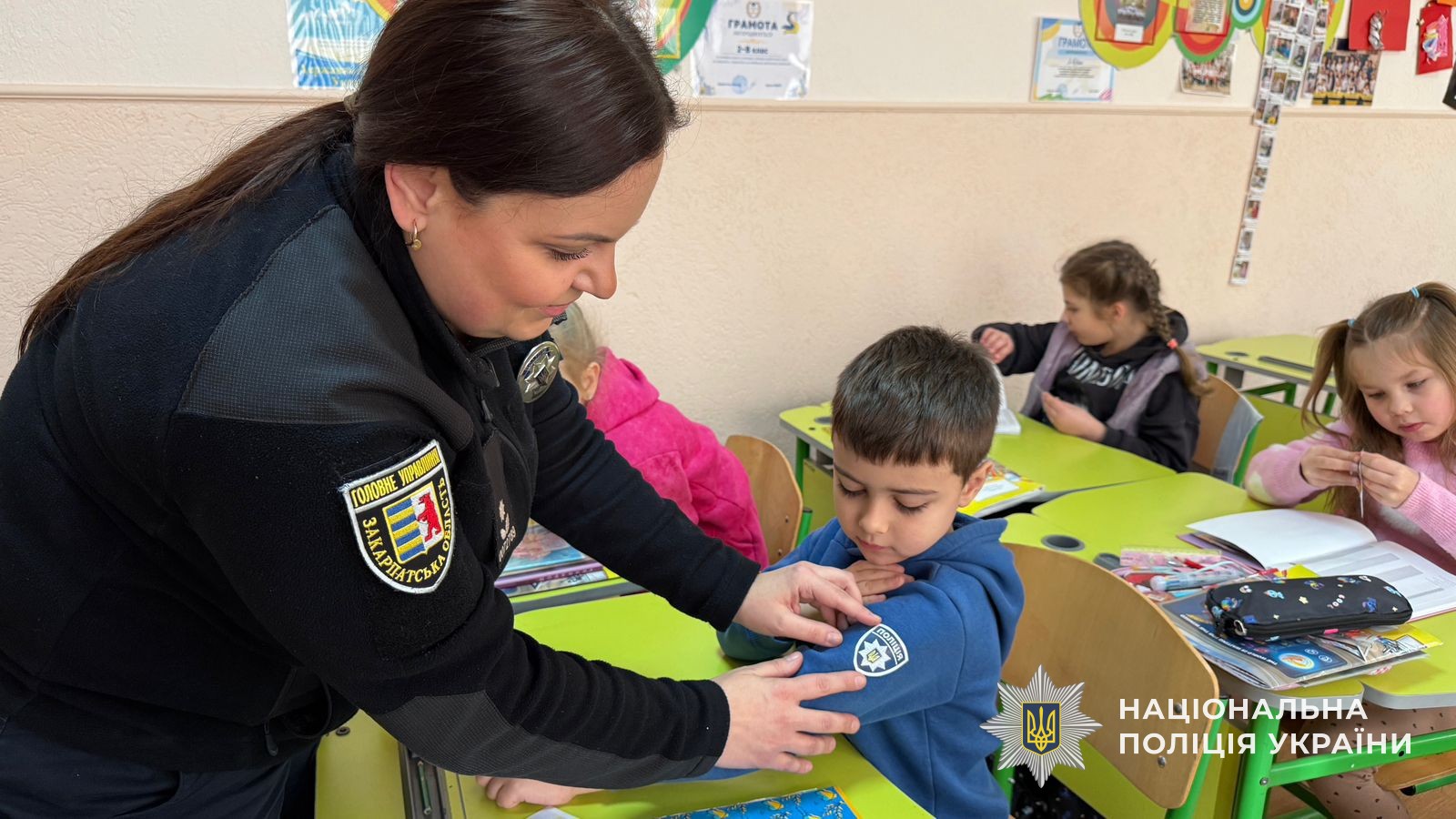 Поліцейська ліпить школяреві на светр наліпку з шевроном поліції