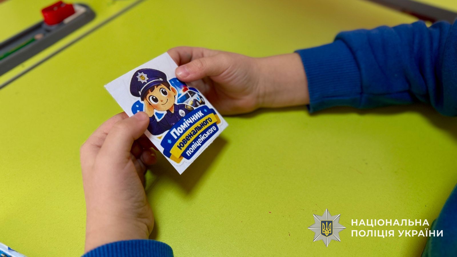 дитина тримає у руках наклейку з написом