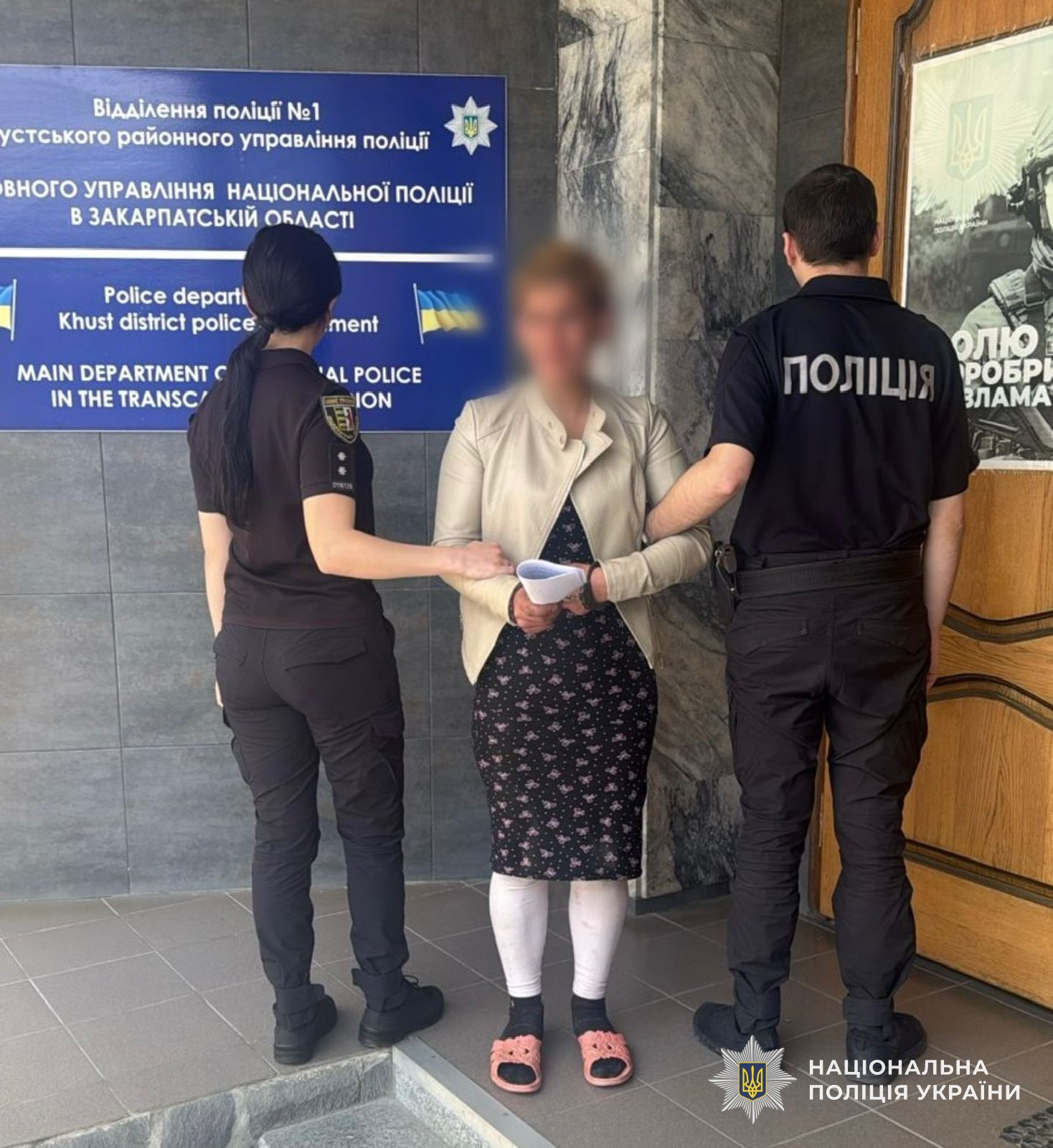 Двоє поліцейських стоять поруч із затриманою жінкою у цивільному, яка передавала в експлуатацію своїх малолітніх дітей