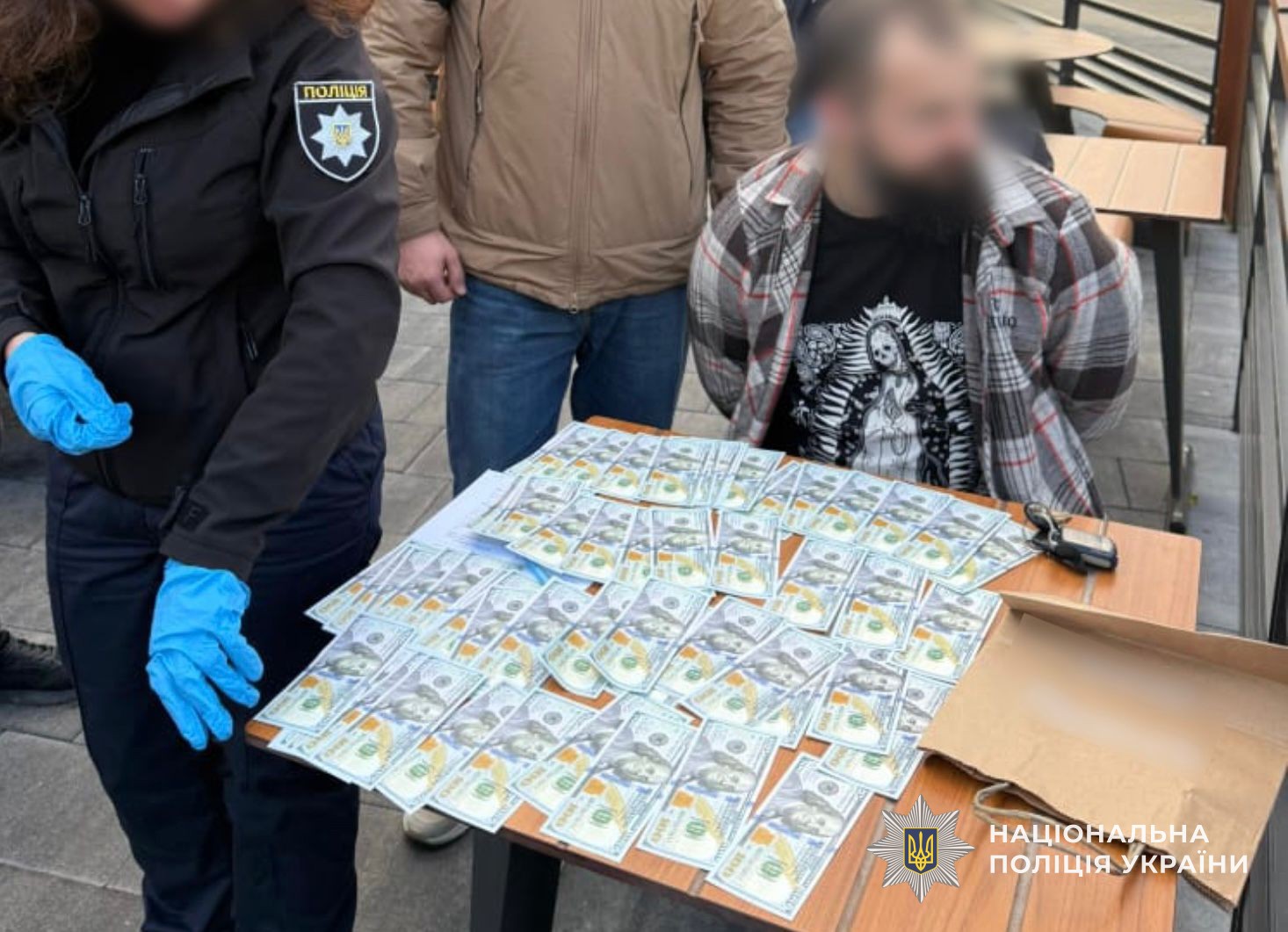 Поліцейські вилучають з місця події готівку, отриману фігурантом за незаконні послуги