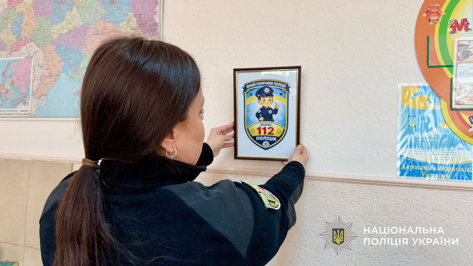 Поліцейська ліпить на стіну наліпку з номером телефону