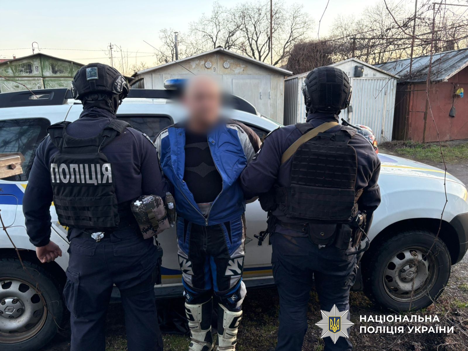 Двоє поліцейських тримають підозрюваного у зберіганні зброї та боєприпасів