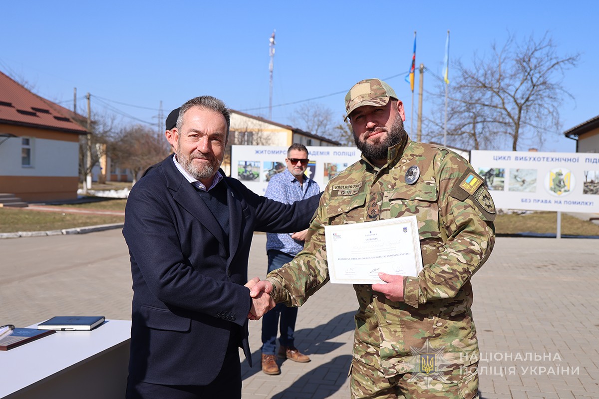 француз вручає сертифікат вибухотехніку