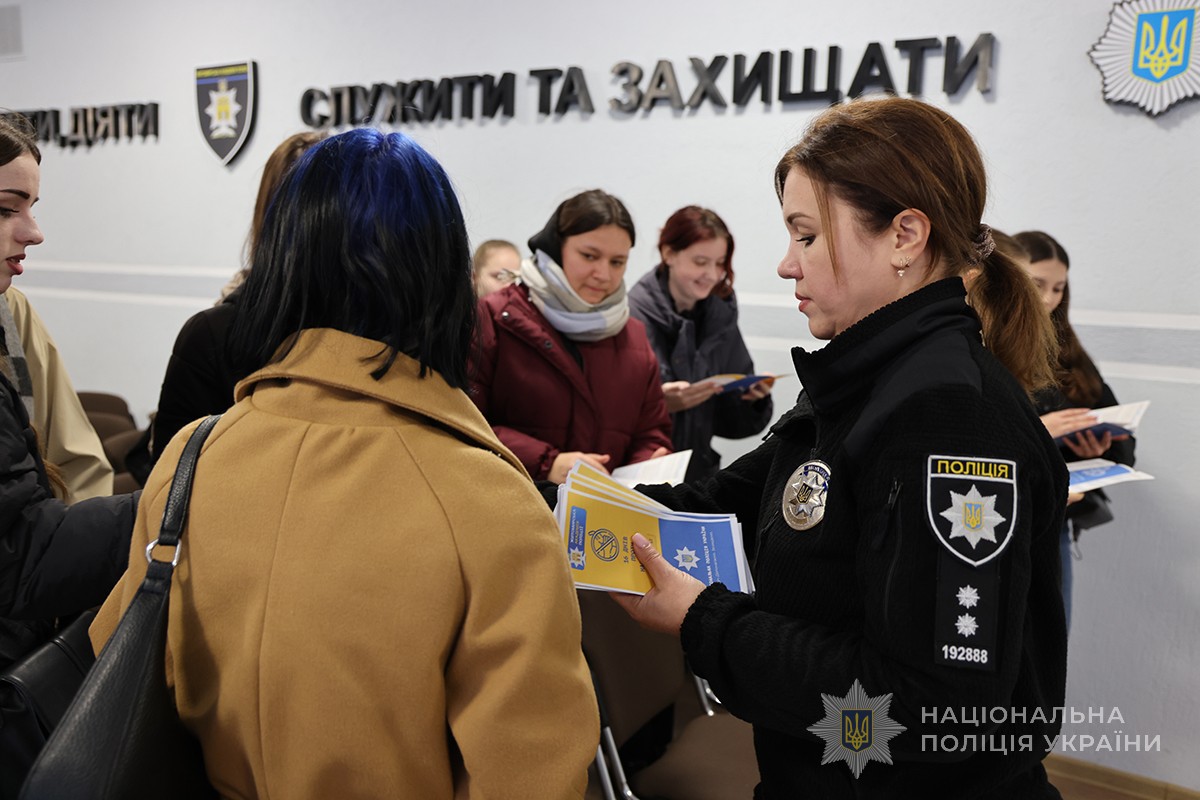 поліцейська роздає студентам буклети