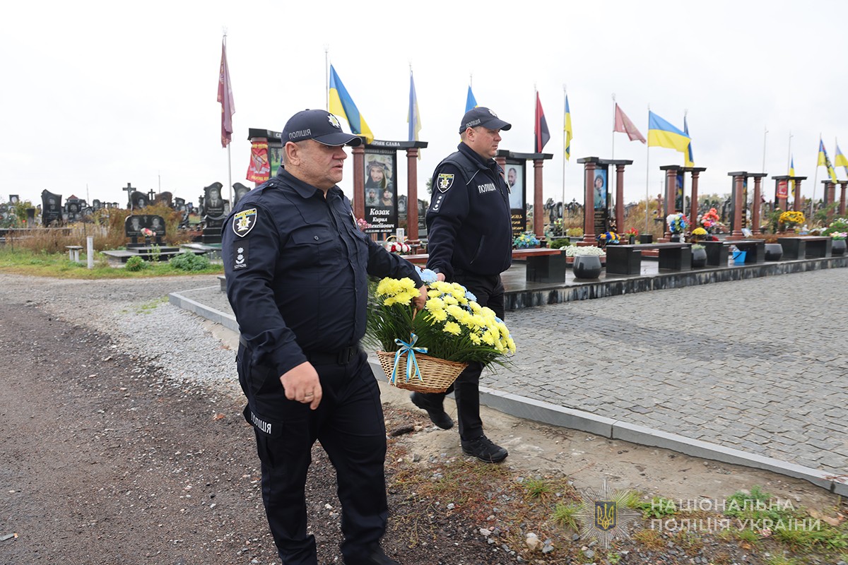 поліцеймькі несуть корзину квітів на кладовищі