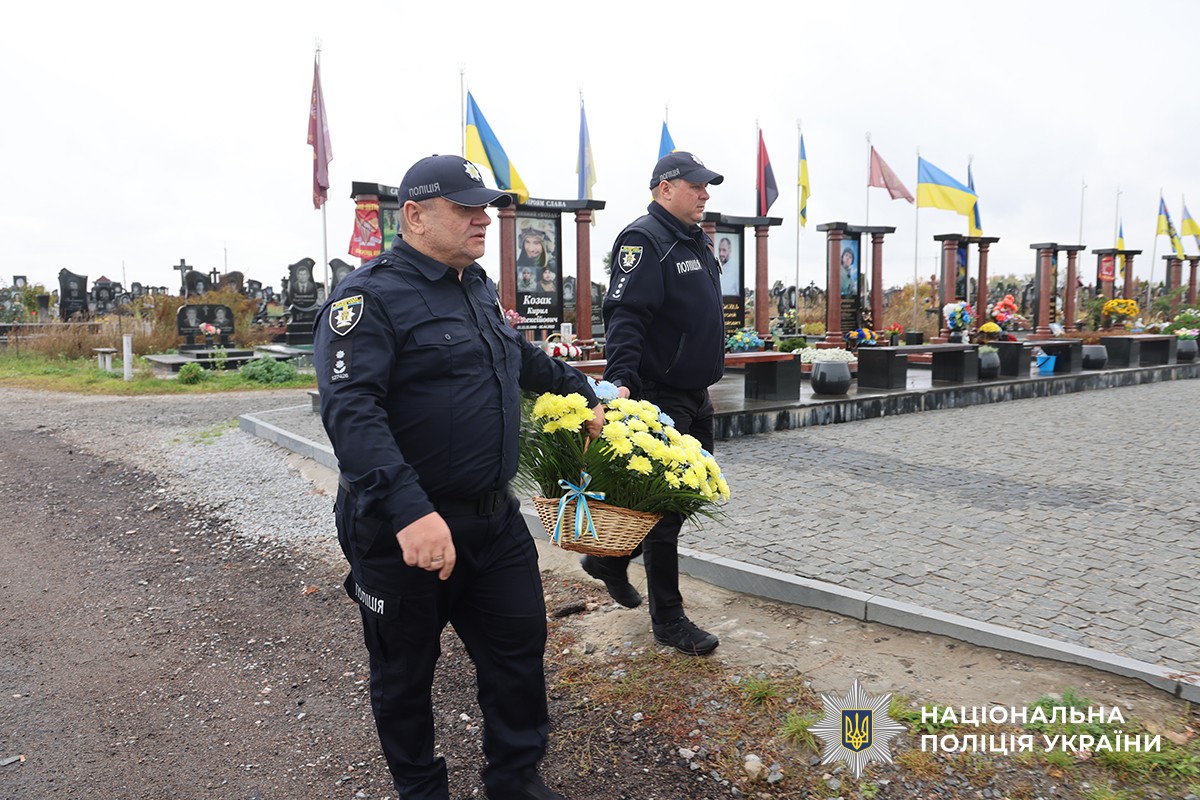 поліцеймькі несуть корзину квітів на кладовищі