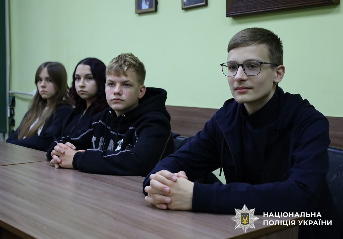 троє ліцеїстів - двоє хлопців та дівчина сидять за партою на уроці