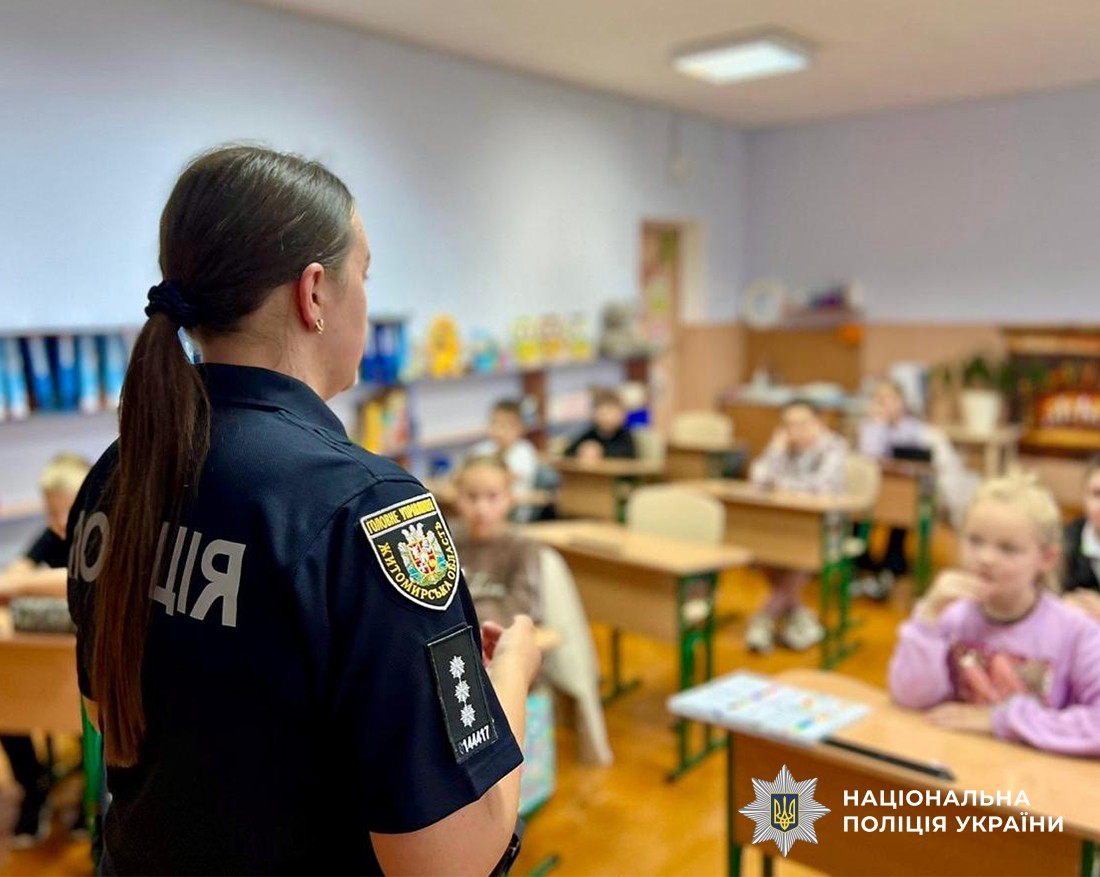 поліцейська, на задньому плані клас, діти сидять за партами