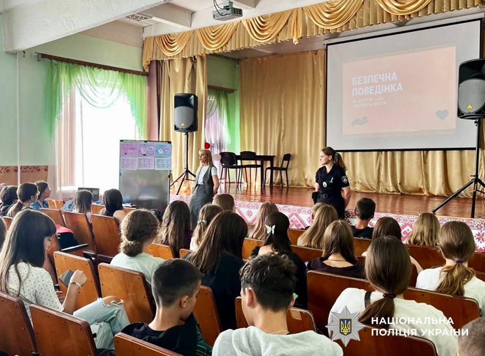 діти сидять в актовому залі, перед ними презентація та поліцейська з прокуроркою