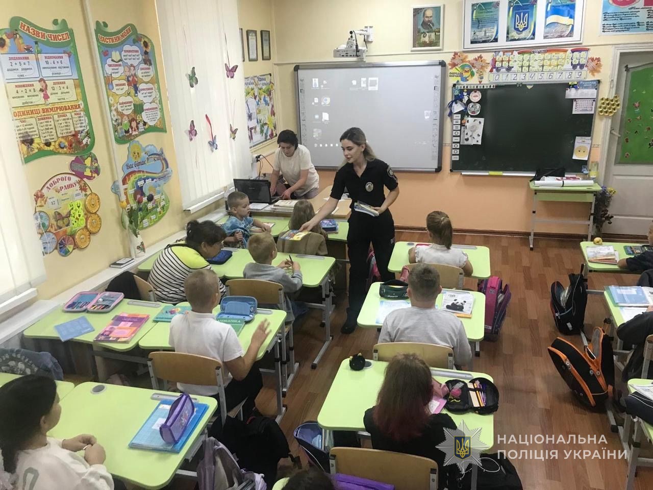 Поліцейська роздає інформаційні матеріали діткам.