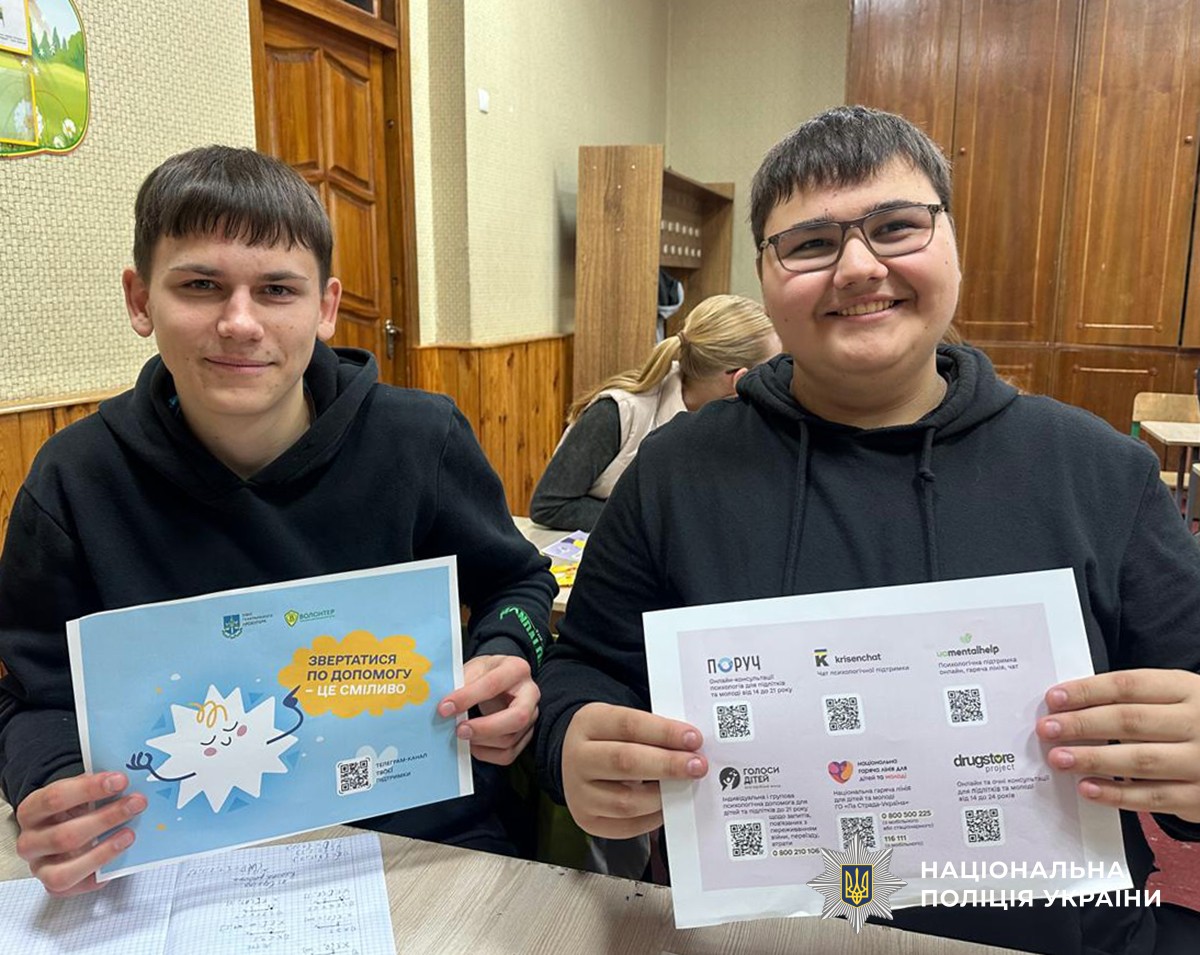 Двоє хлопців-підлітків у класі тримають інформаційні брошури