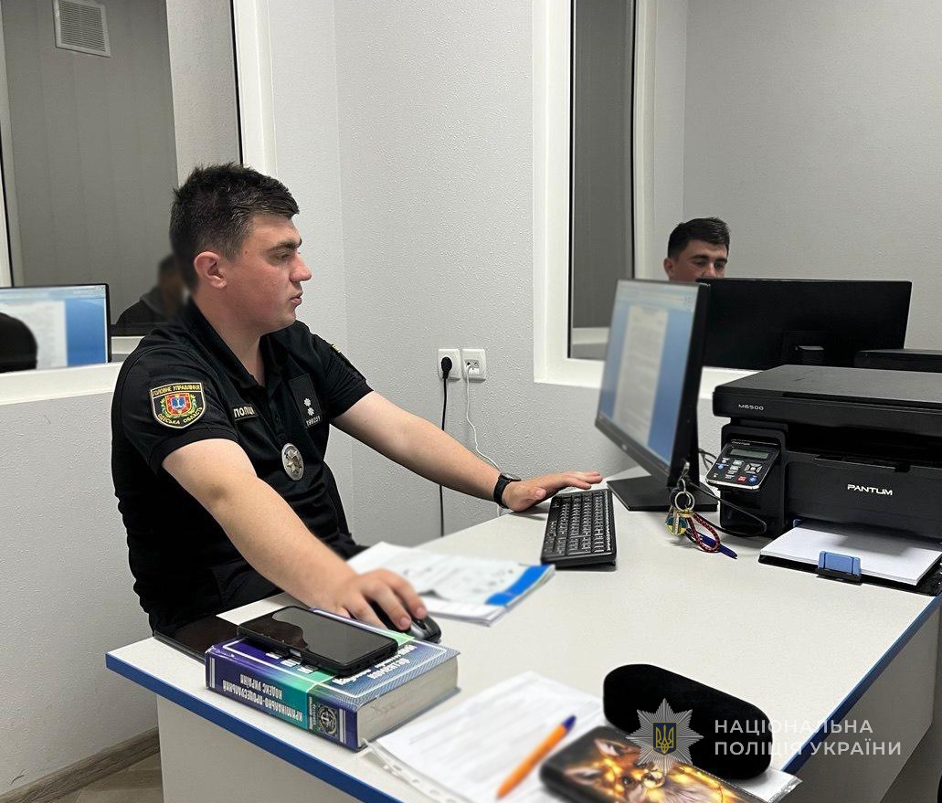 Поліцейський на робочому місці фіксує дані правопорушника на робочому комп'ютері