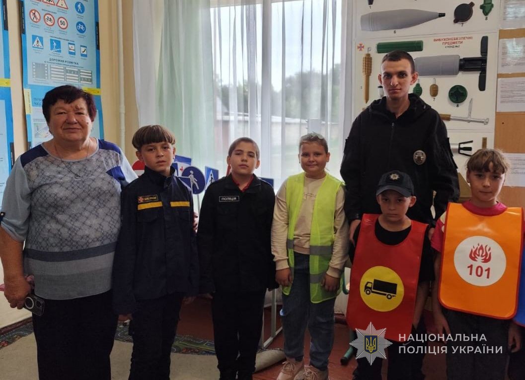 Поліцейський разом із дітками та вчителем фотографуються в класі.