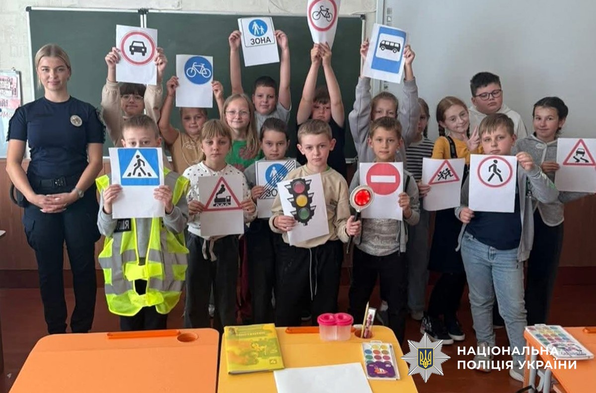 Поліцейська та діти в навчальному класі показують зображення дорожніх знаків
