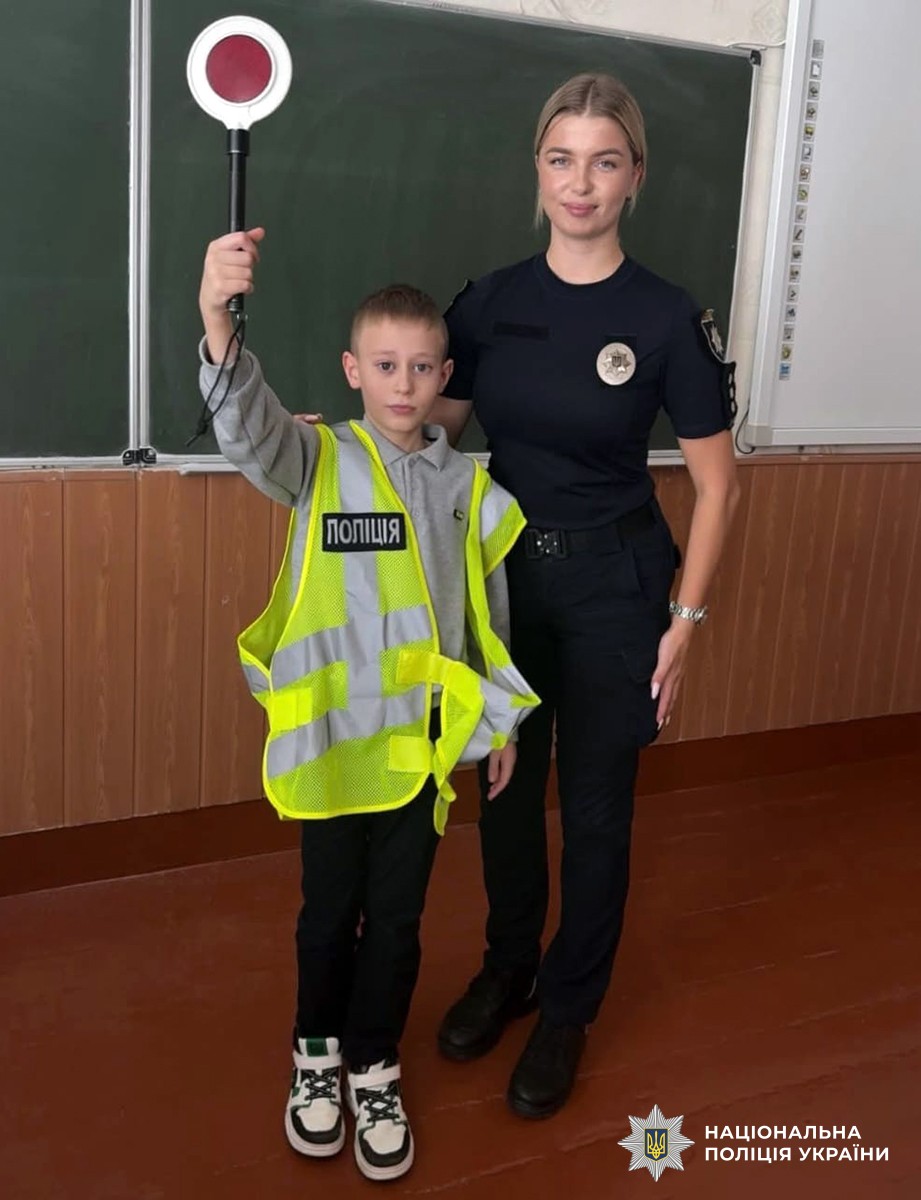 поліцейська та хлопчик у світловідбивному жилеті в навчальному класі
