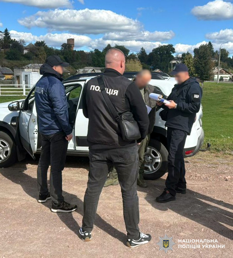 Двоє поліцейських, працівник ДБР та фігурант стоять поблизу білого автомобіля.