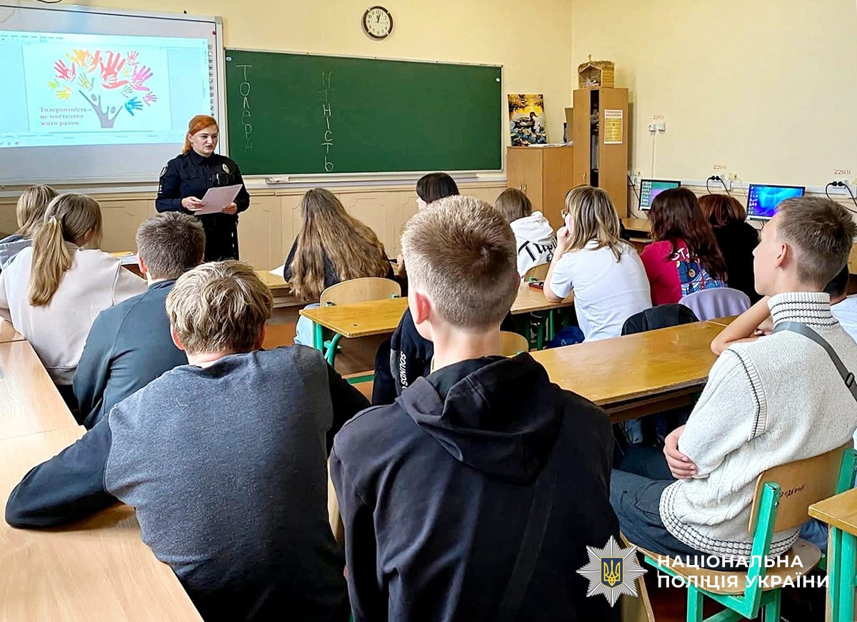 діти в навчальному класі за партами, перед ними поліцейська
