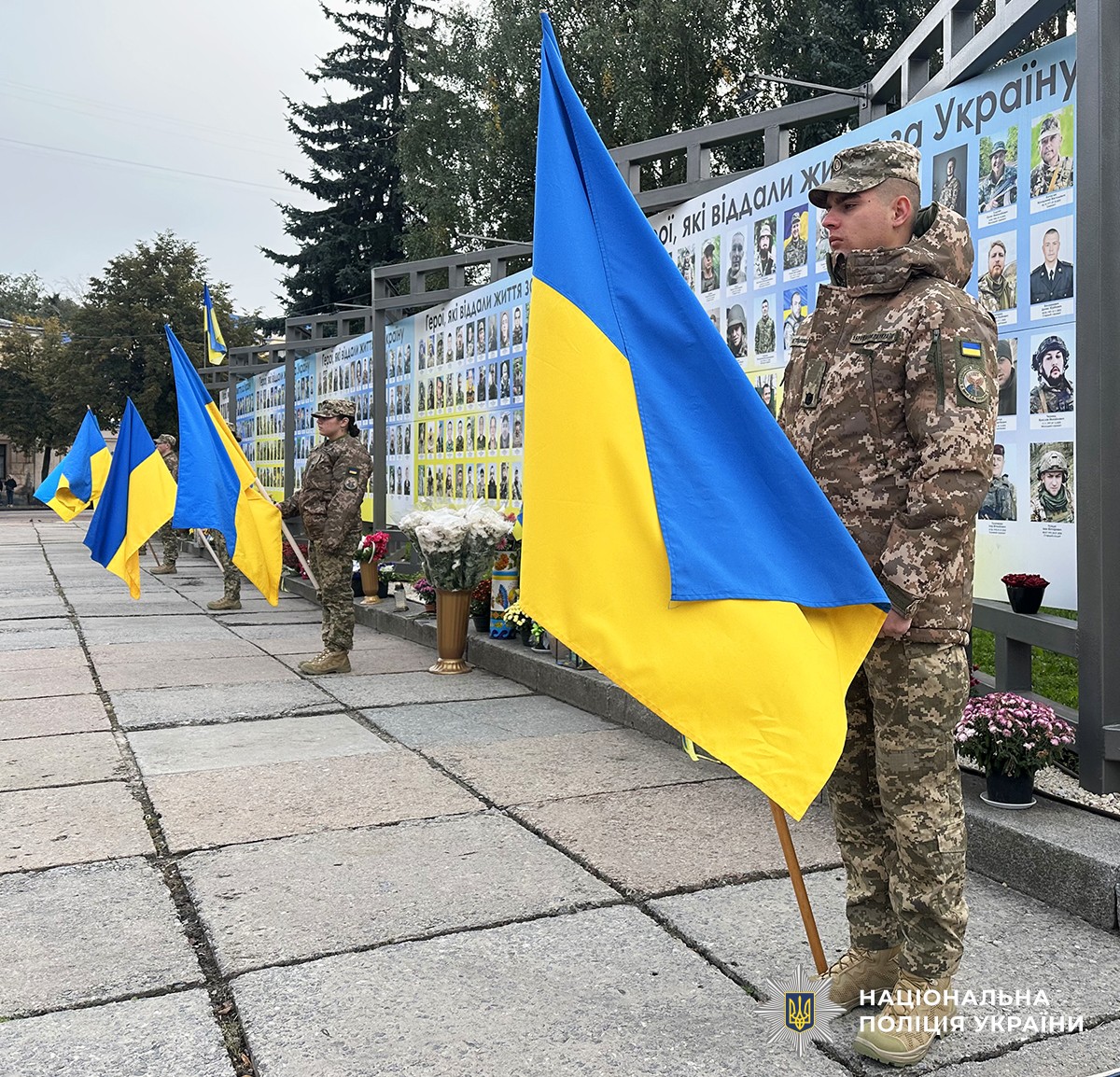 Курсанти стоять із синьо-жовтими прапорами біля Алеї Героїв