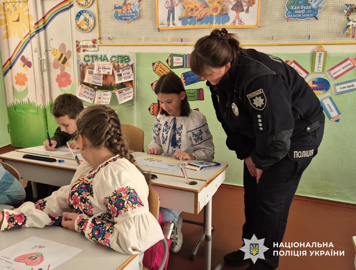 Поліцейська нахилилася до дівчинки, яка сидить за партою