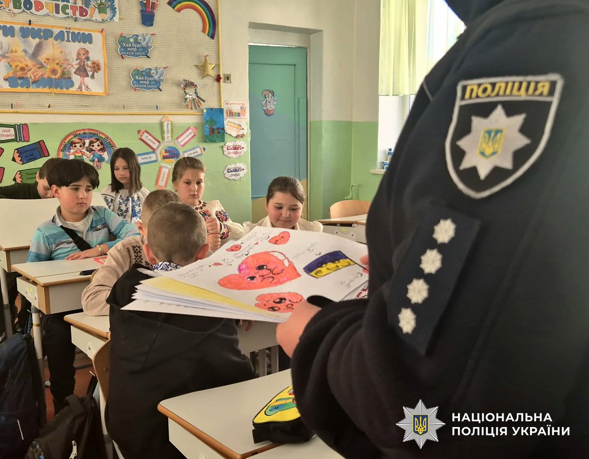 поліцейська тримає в руках дитячі малюнки