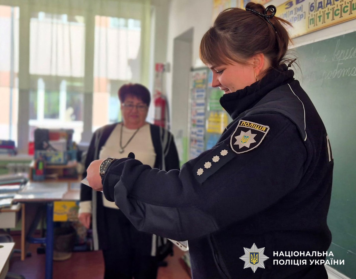 Поліцейска дивиться на щось у своїх руках. позаду стоїть вчителька
