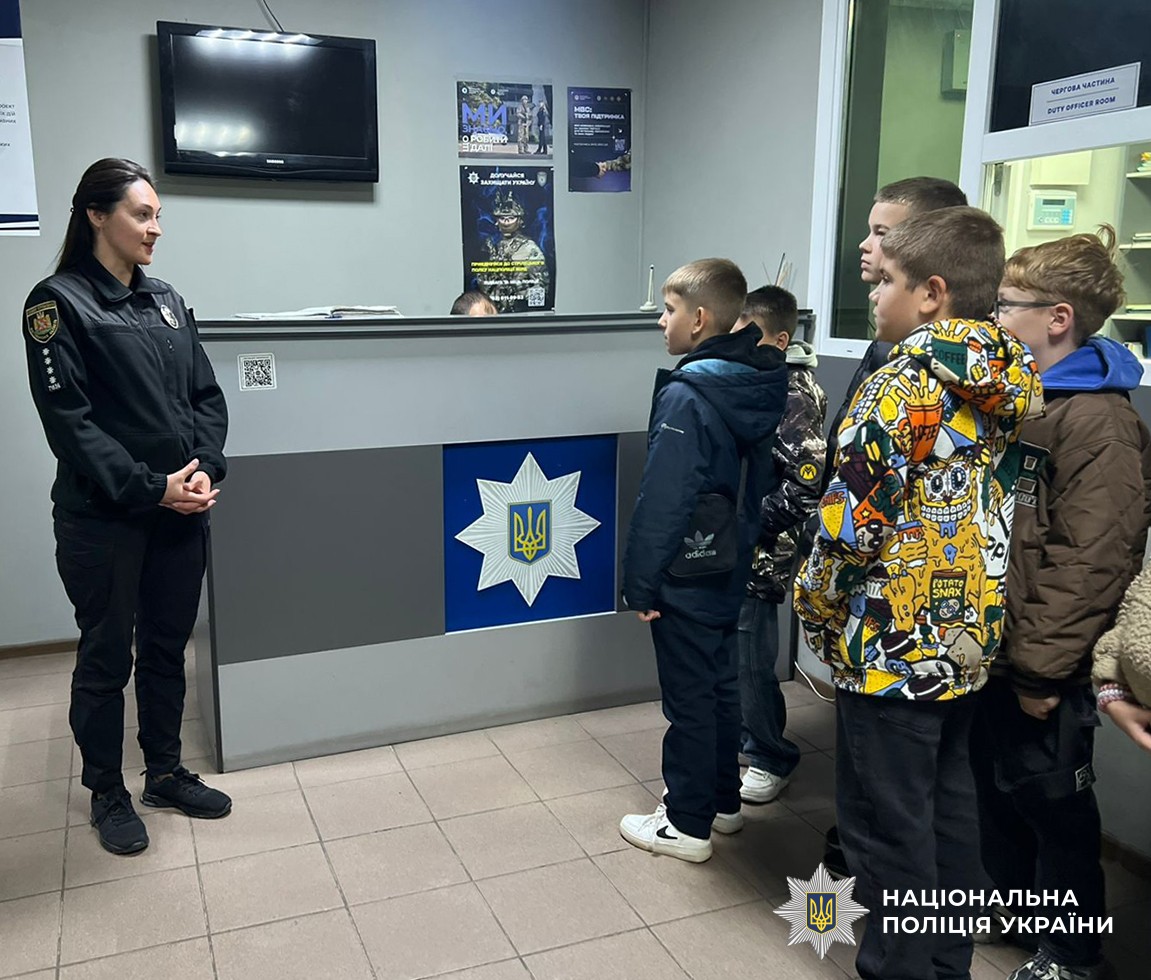 Діти в приміщенні районного відділу поліції біля чергової частини, перед ними стоїть поліцейська.