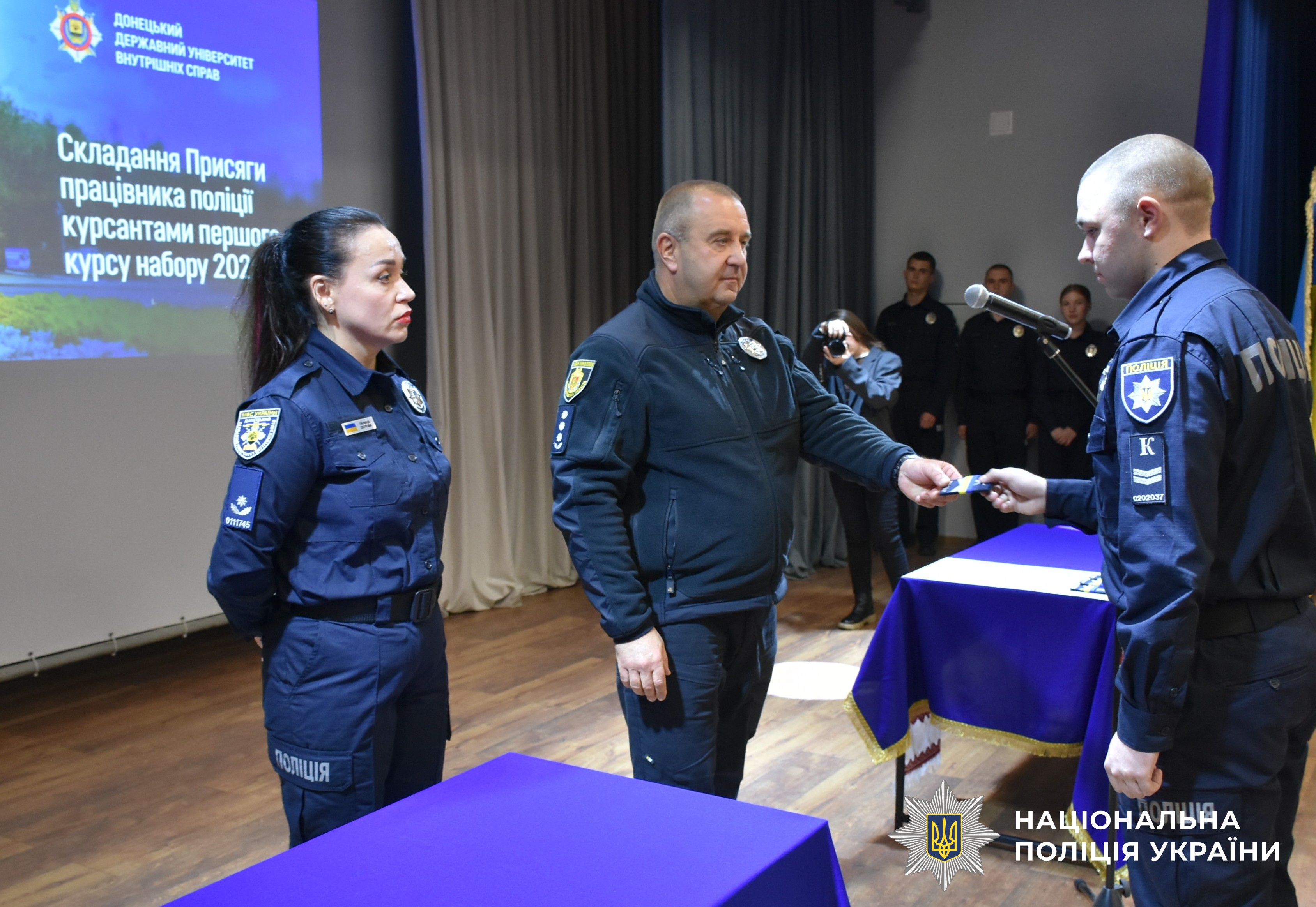 керівник поліції області вручає курсантку погони