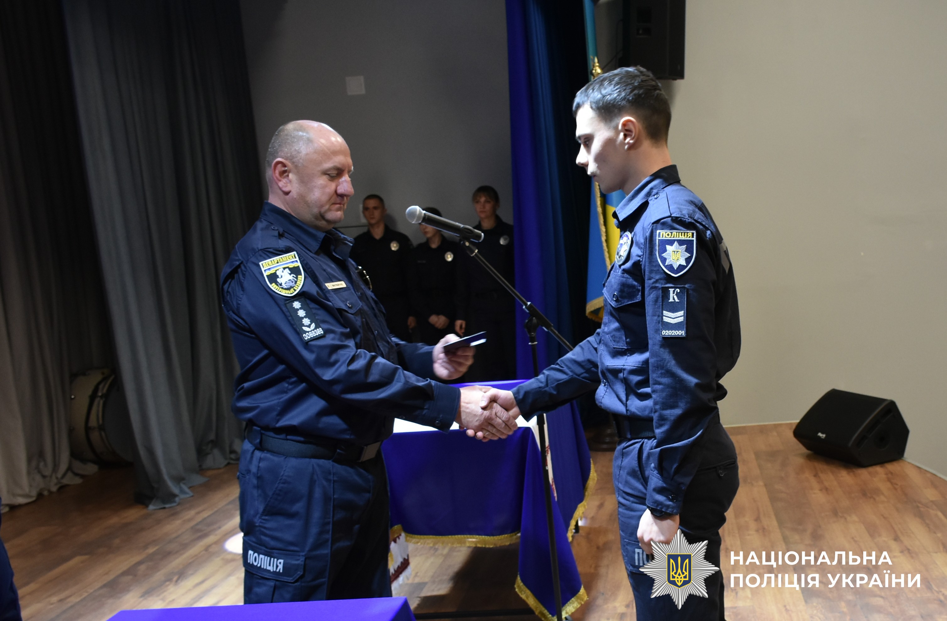керівник міжрегіонального підрозділу вручає курсанту погони
