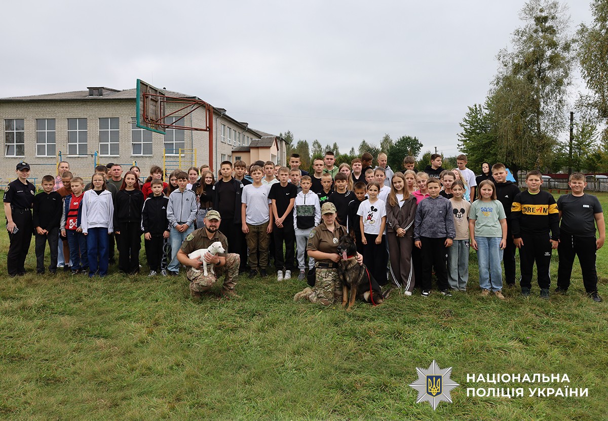 На спільному фото позують група дітей, поліцейські кінологи зі службовими собаками