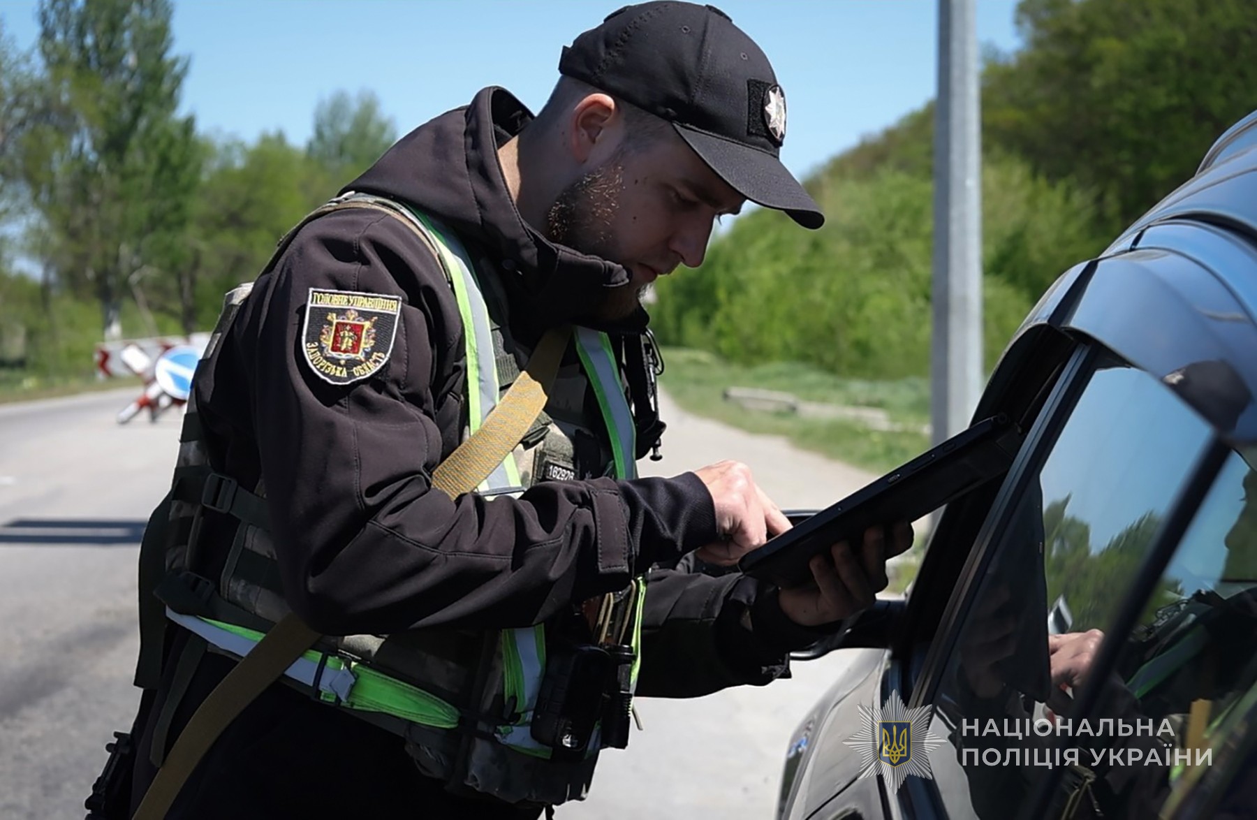 Поліцейський перевіряє транспортний засіб на блокпосту.