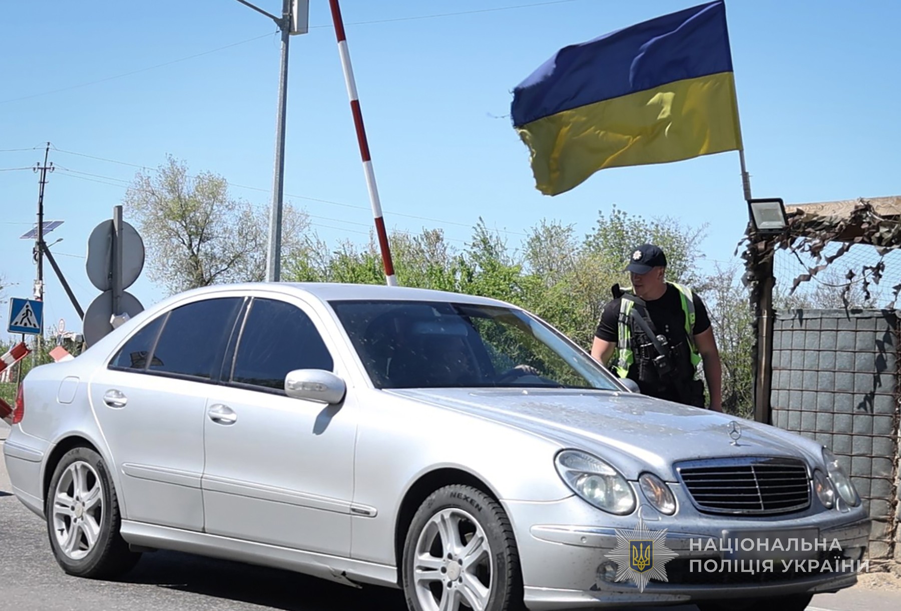 Поліцейський перевіряє транспортний засіб на блокпосту.