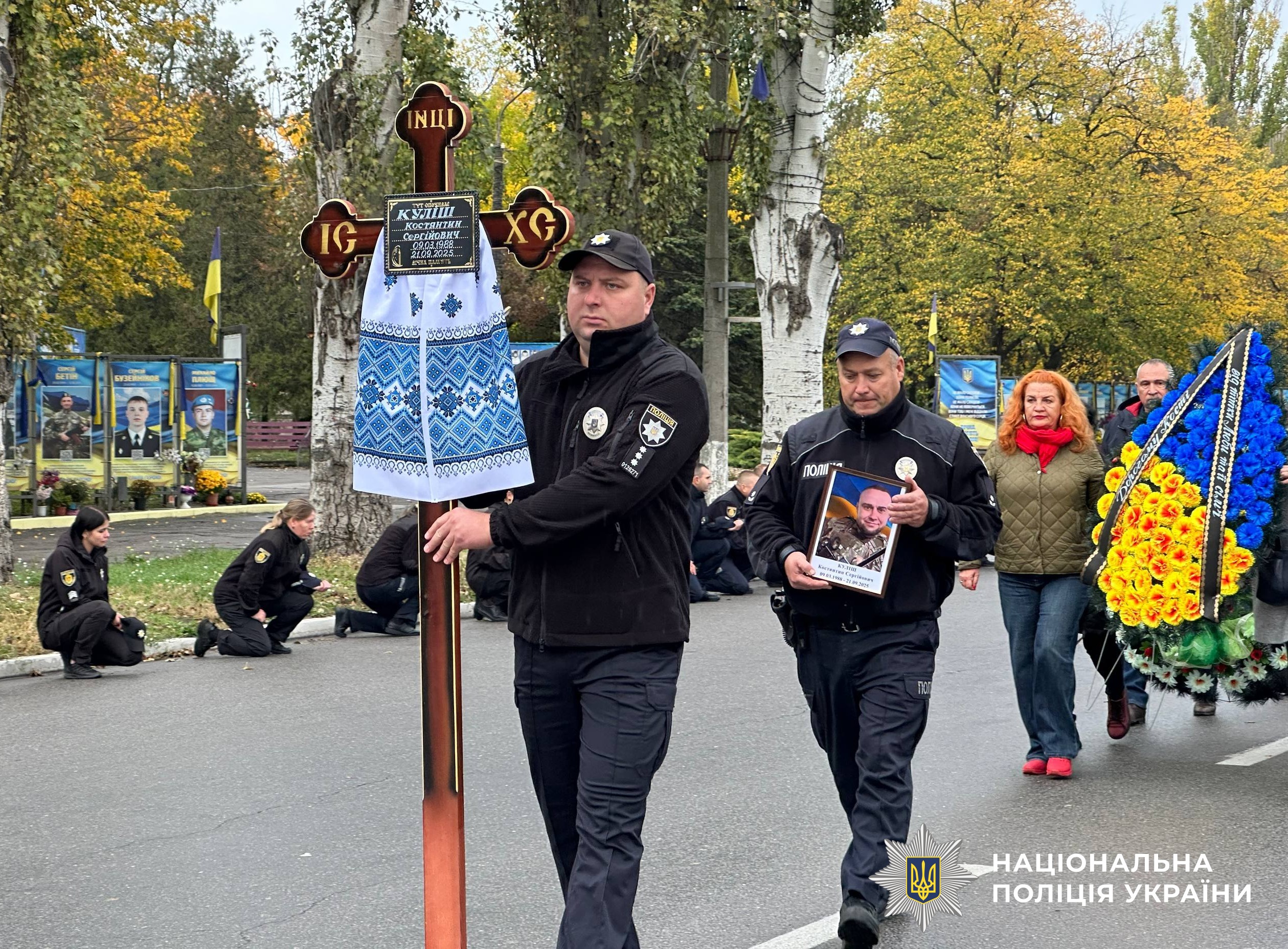 поліцейські несуть хрест для поховання та портрет загиблого