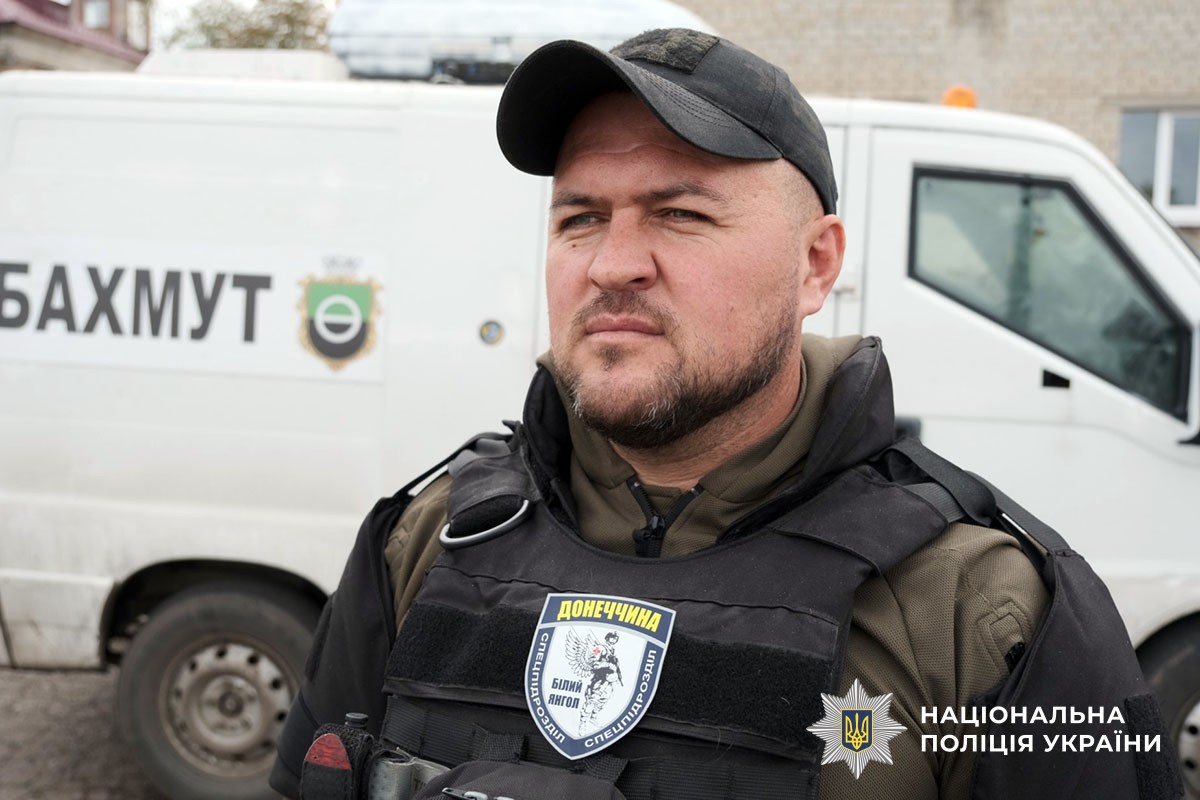 Поліцейський стоїть біля евакуаційної машини