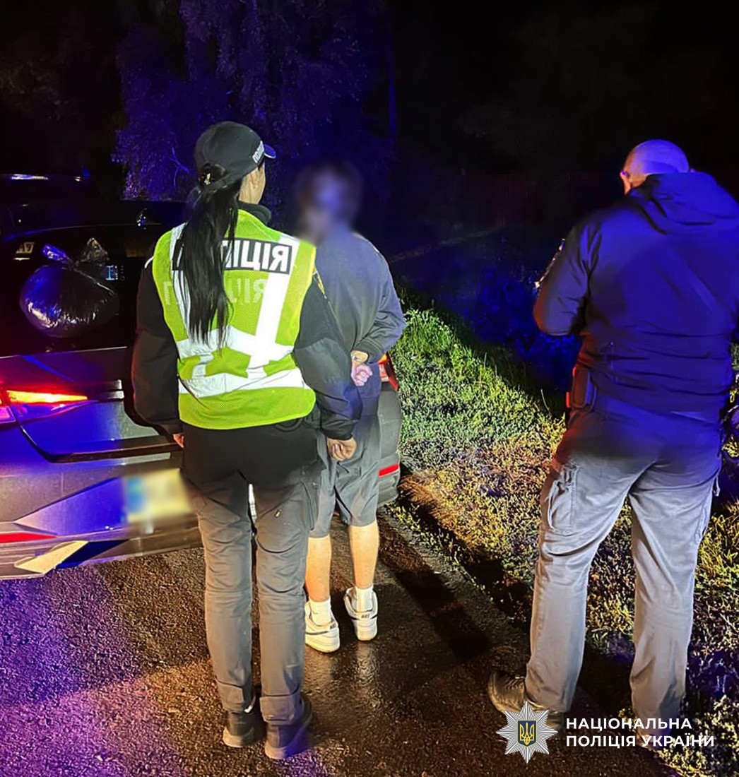 поліцейські стоять на вулиці із затриманим, поряд із ними автомобіль, на багажнику якого лежить пакет із наркотичними речовинами