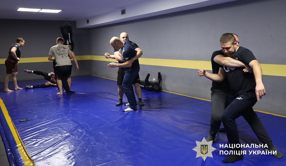 Учасники розділилися по двоє та відпрацьовують прийоми.
Подія відбувається у спортивному залі.