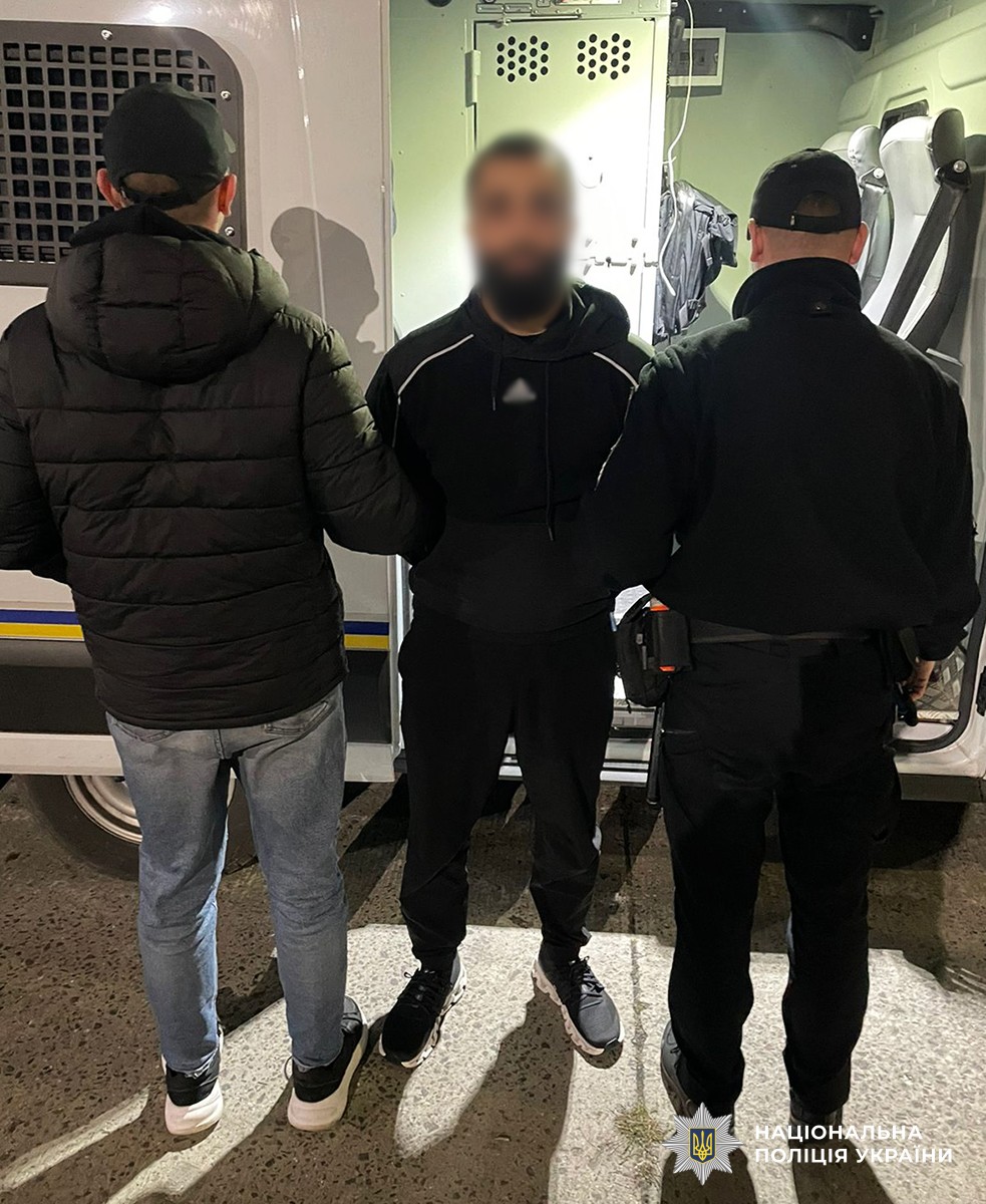 двоє поліцейських тримають затриманого