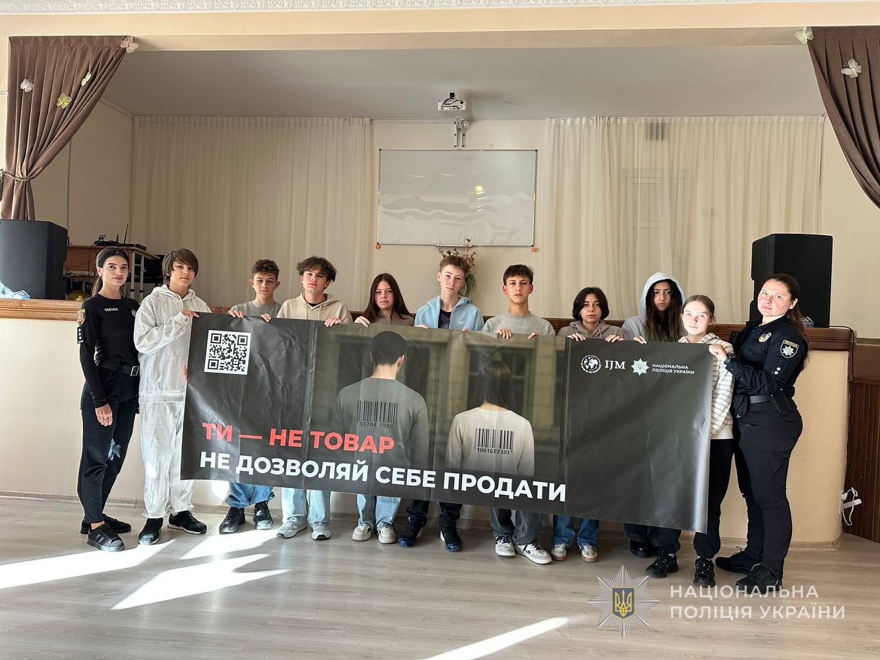Учні разом із поліцейськими тримають плакат із надписом: "Ти - не товар. Не дозволяй себе продати"