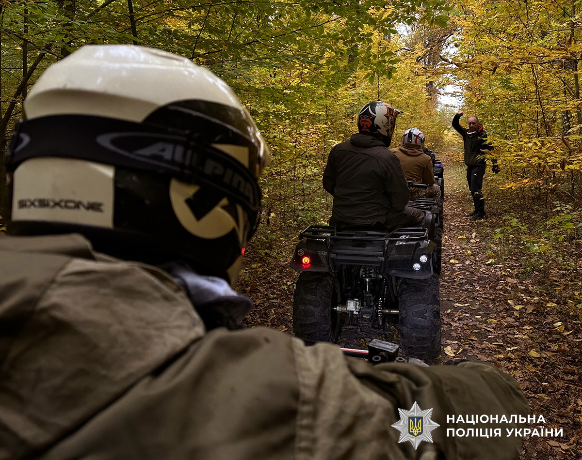 На передньому плані зі спини за кермом квадроциклу сидить чоловік. На задньому плані ще четверо чоловіків на квадроциклах, усі у захисних шоломах, їм інструктор щось пояснює.