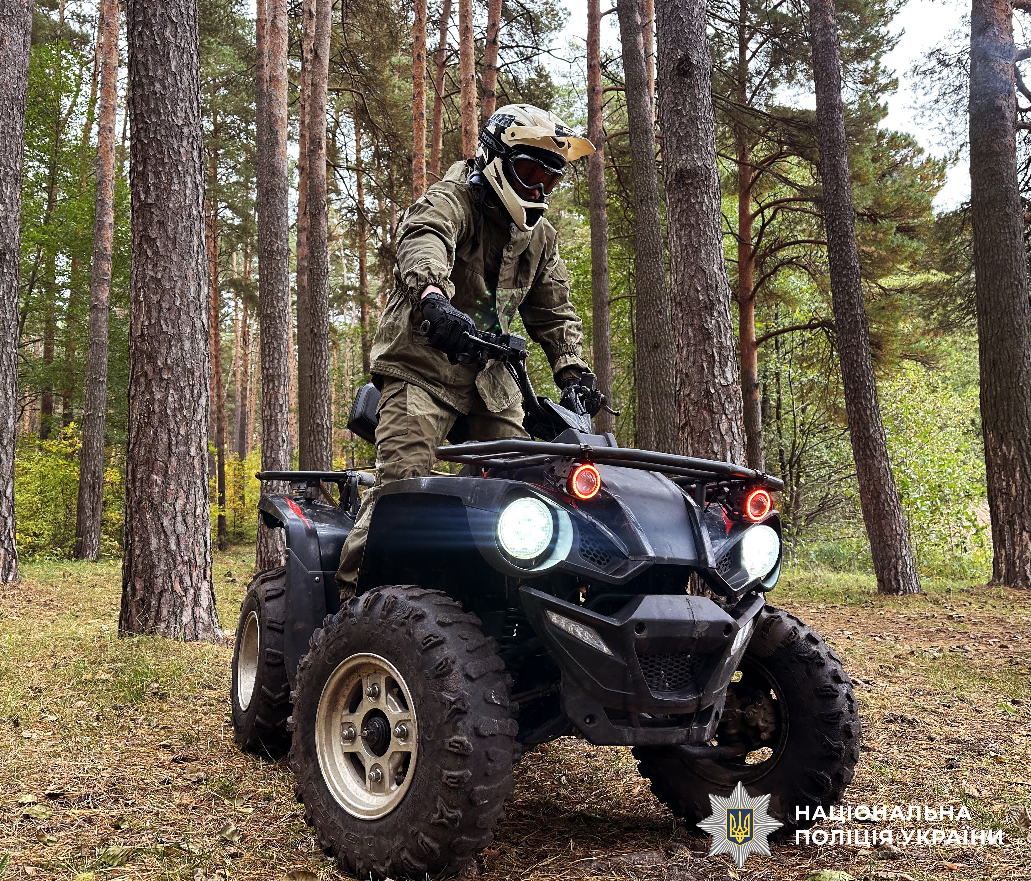 Чоловік у камуфляжній формі та захисному шоломі стоїть напівстоячи на квадроциклі.