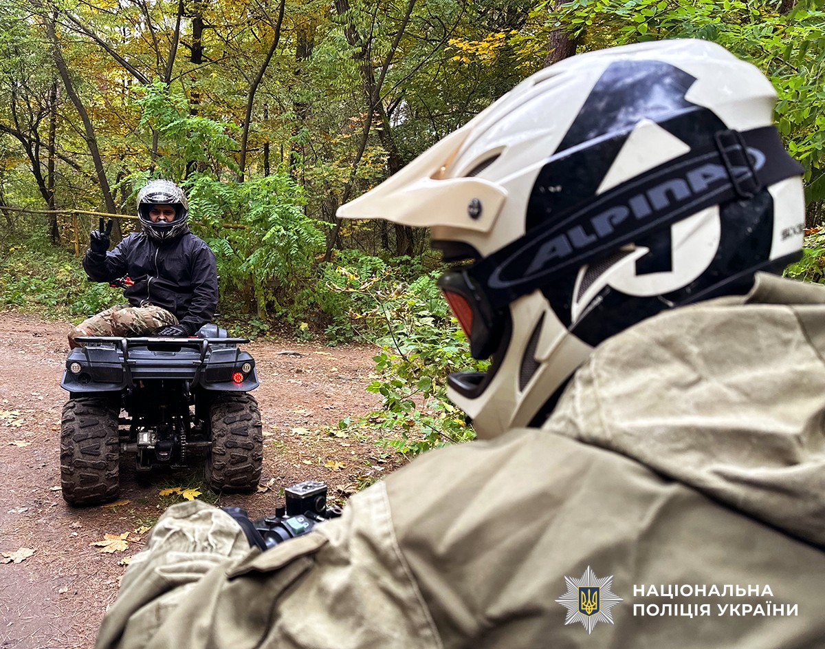 На передньому плані зі спини за кермом квадроциклу сидить чоловік. На задньому плані інший чоловік сидить на квадроциклі та позує для фото.